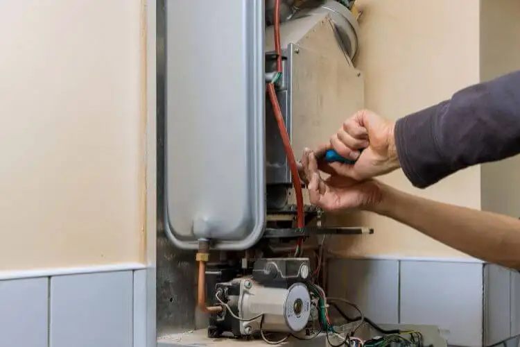 A licensed plumber carefully adjusts a hot water unit – the kind of pro touch that keeps your system humming safely.